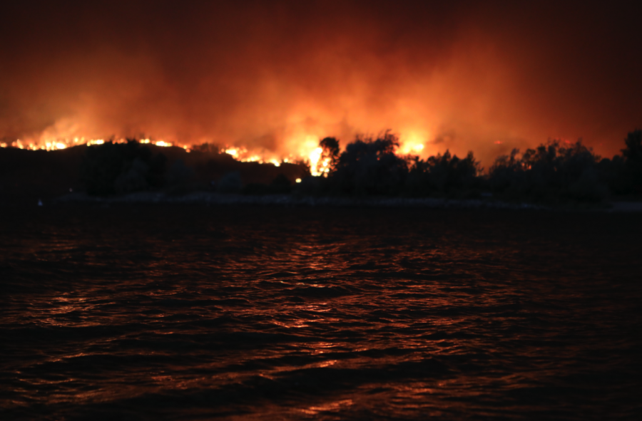 <who> Photo credit: Aaron Hemens </who> The McDougall Creek Wildfire burning above the hills of West Kelowna in syilx Okanagan homelands on Aug. 17, 2023, reflected in Okanagan Lake.