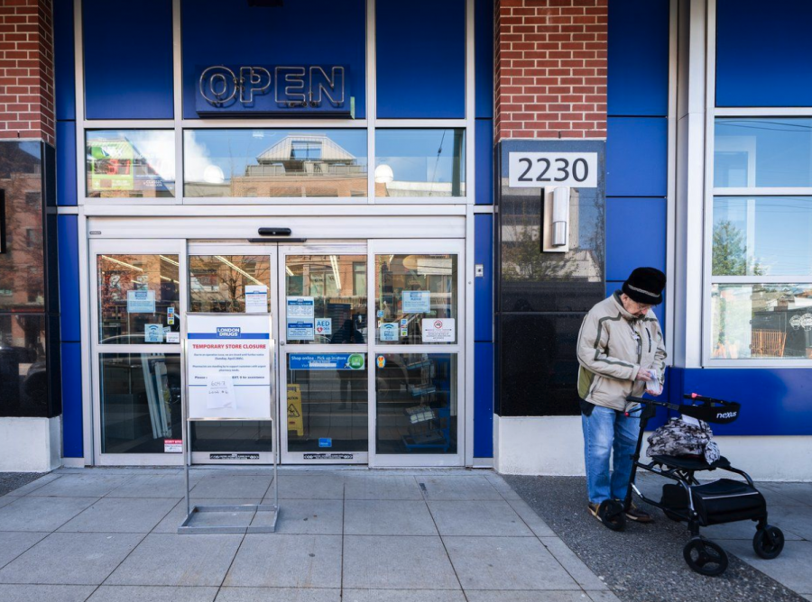 <who> Photo credit: Canadian Press </who> A woman waits outside of the London Drugs Broadway and Vine location in Vancouver on Monday.